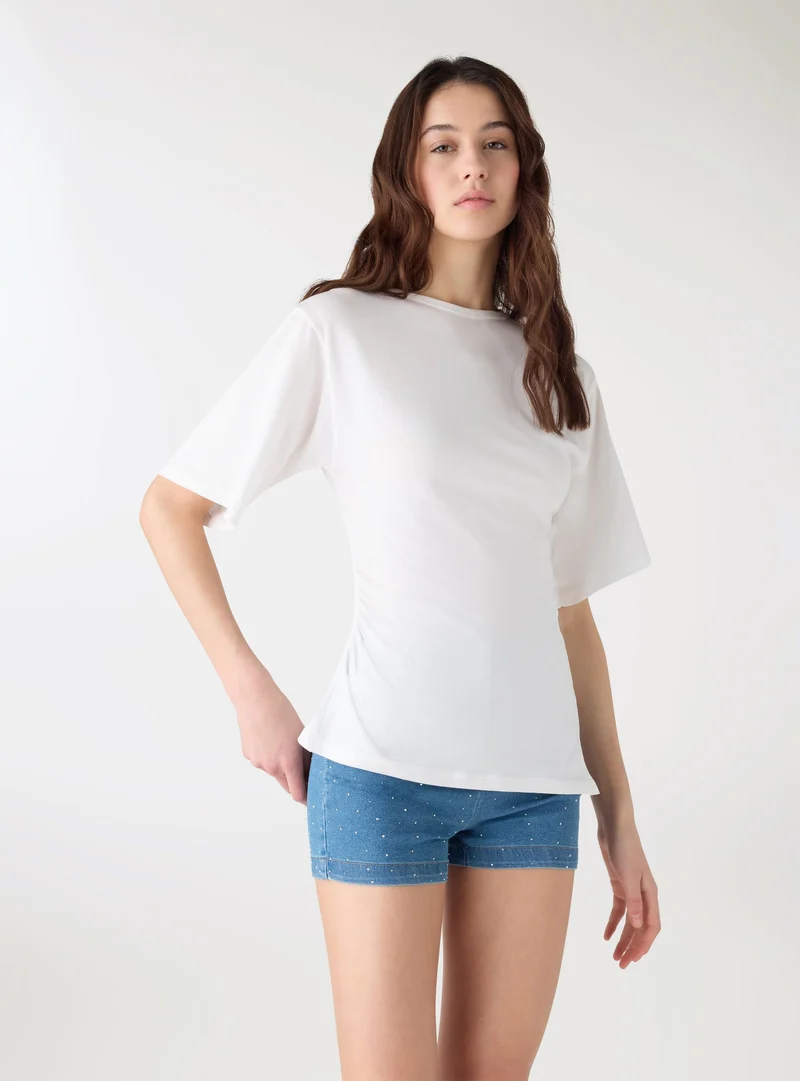 T-shirt con arricciatura laterale e fondo asimmetrico