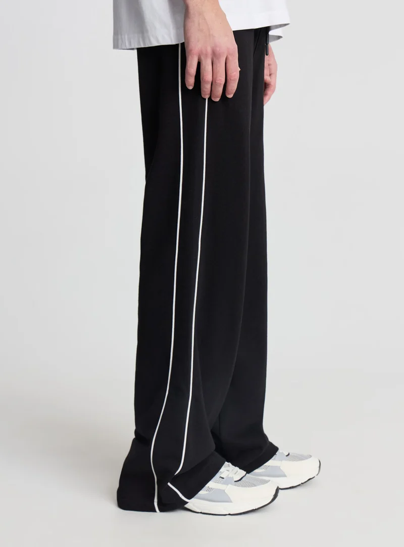 Pantaloni tuta wide leg con piping
