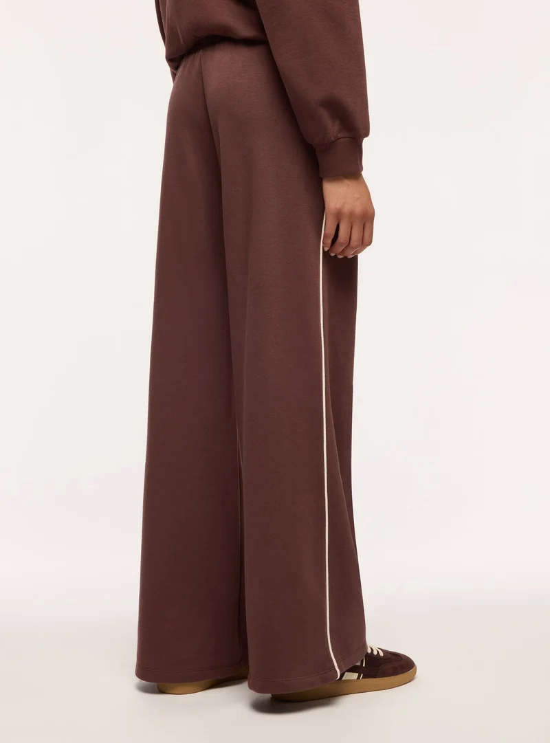 Pantaloni tuta maxi con piping laterale