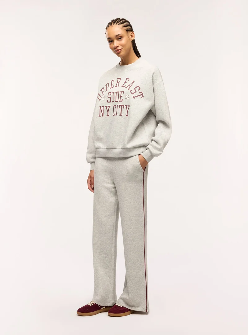 Pantaloni tuta wide leg con piping laterale