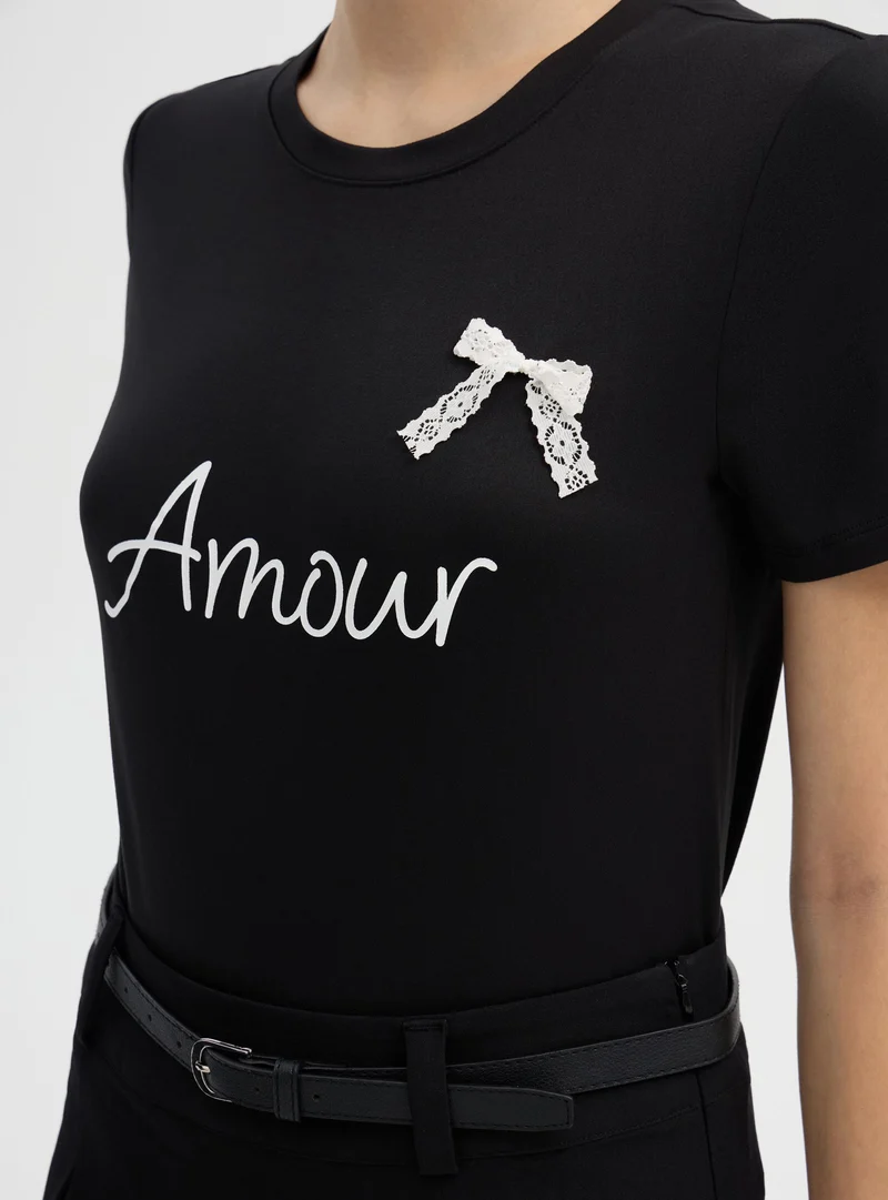 T-shirt aderente con scritta e fiocco in pizzo