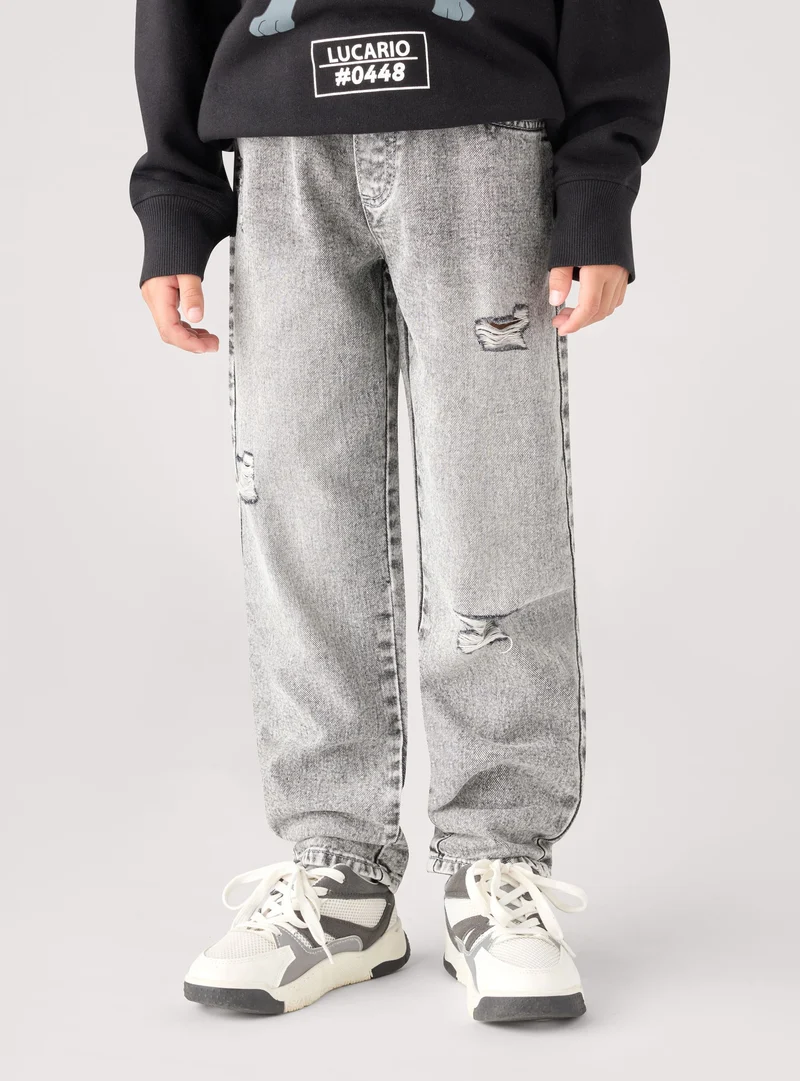 Jeans jogger da bambino con strappi e coulisse