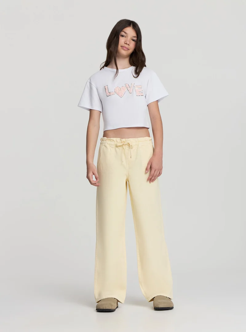 T-shirt crop con scritta effetto petali