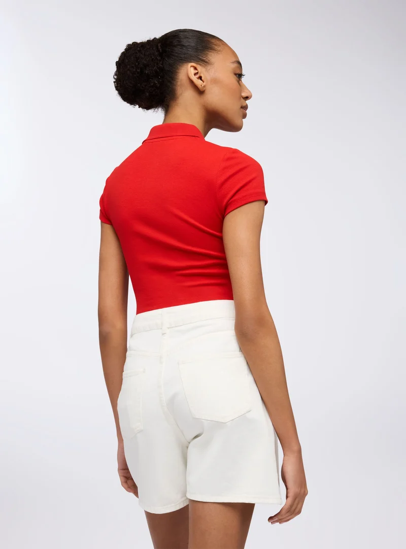 Polo crop con ricamo stile college