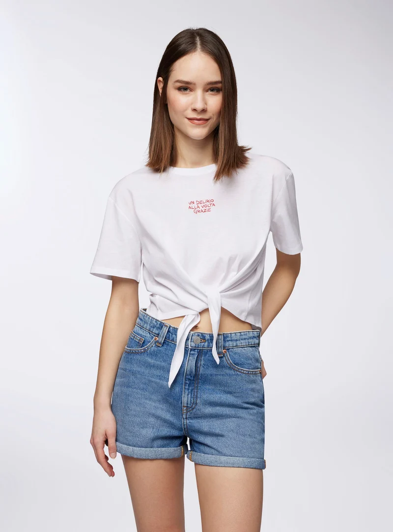 T-shirt crop ampia con scritta e nodo
