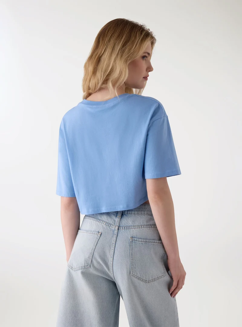 T-shirt crop ampia con scritta