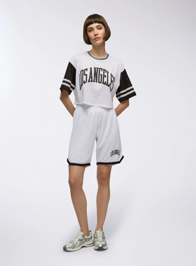 T-shirt crop in rete con stampa college