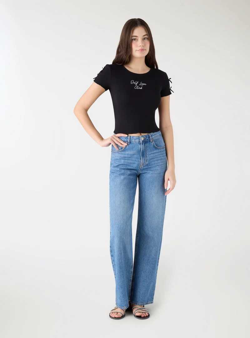 T-shirt crop con scritta e fiocchi