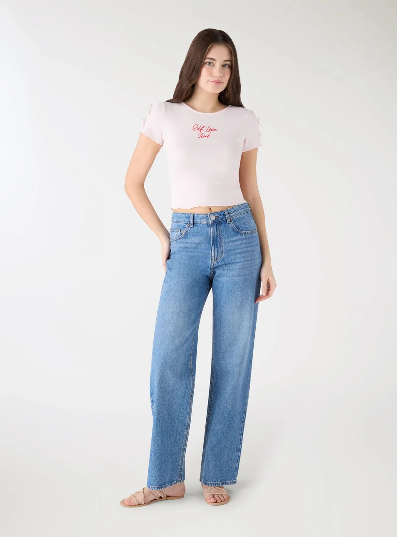 T-shirt crop con scritta e fiocchi