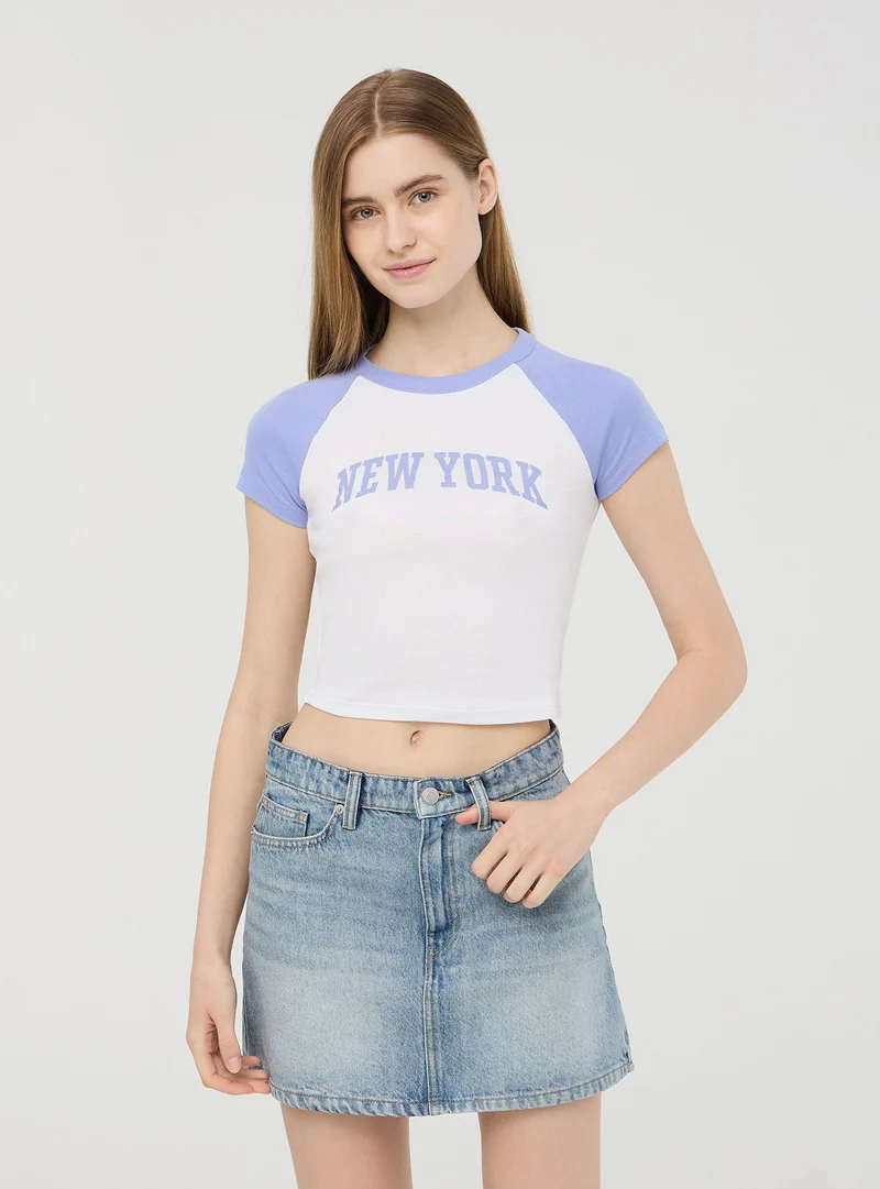 T-shirt crop raglan con stampa college