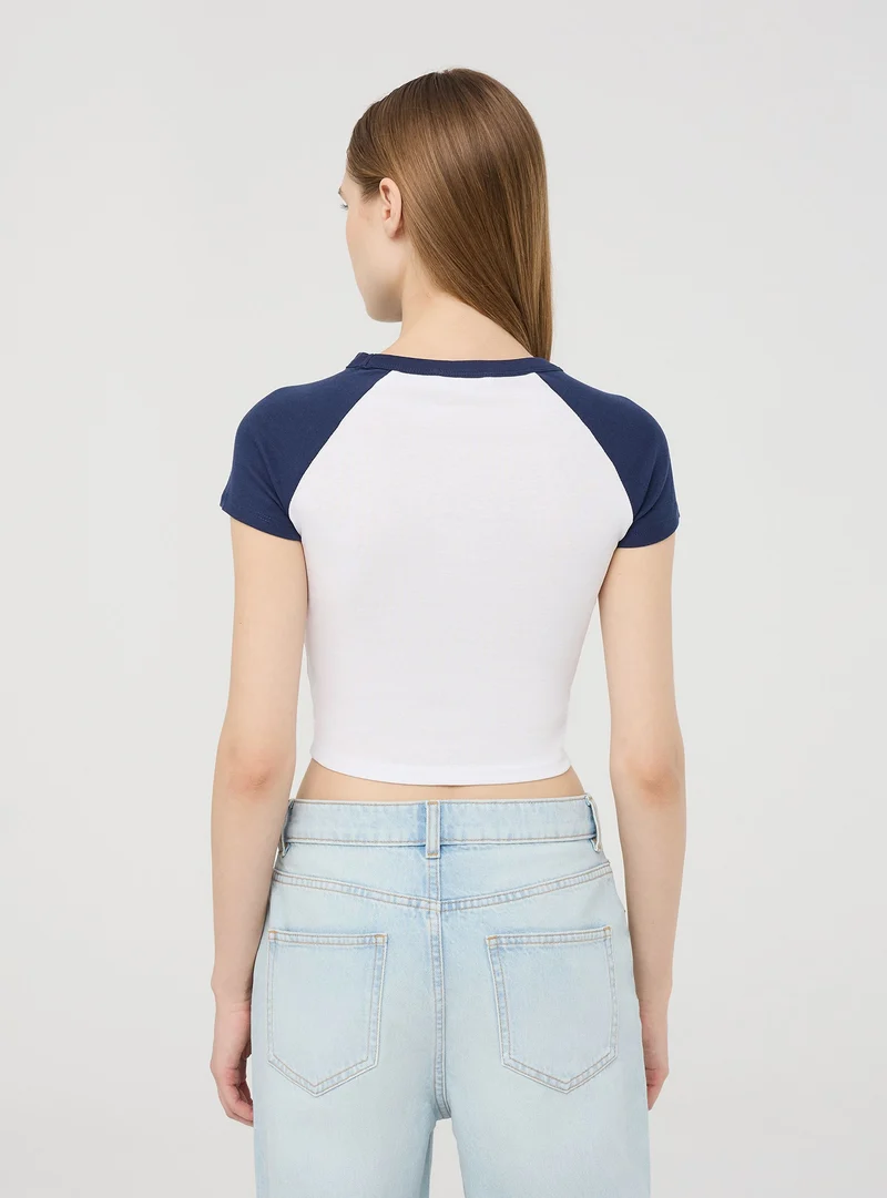 T-shirt crop raglan con stampa college
