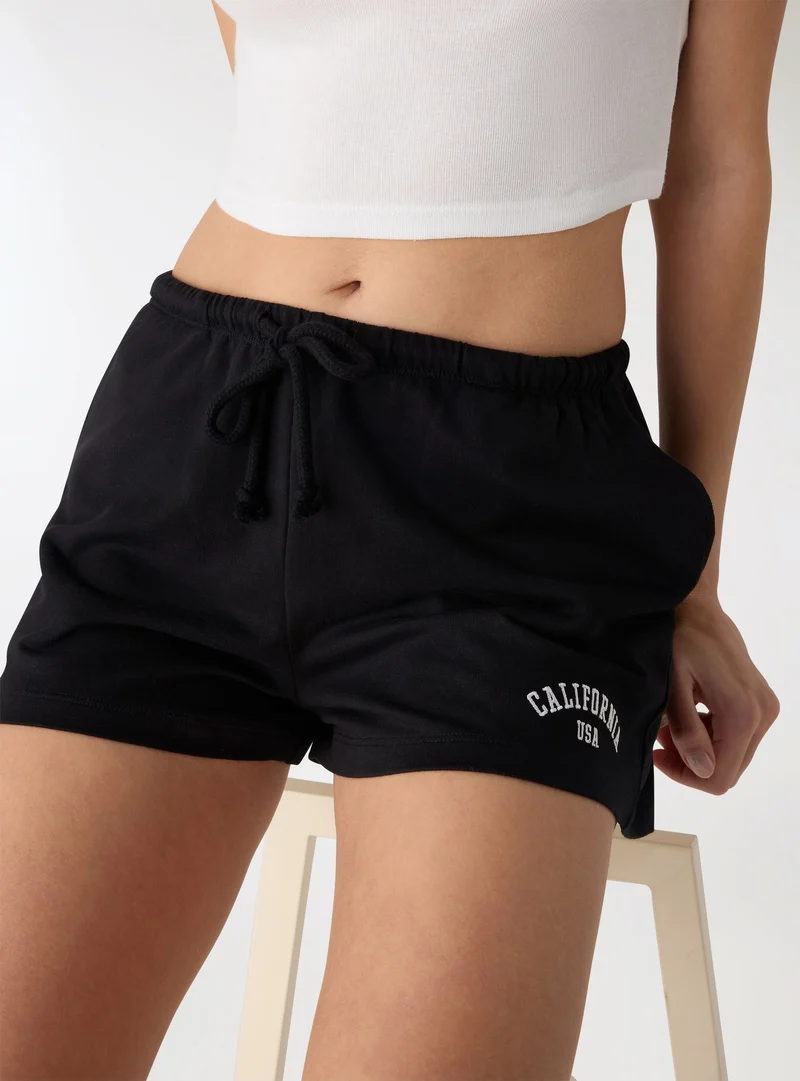 Pantaloni tuta corti con ricamo college