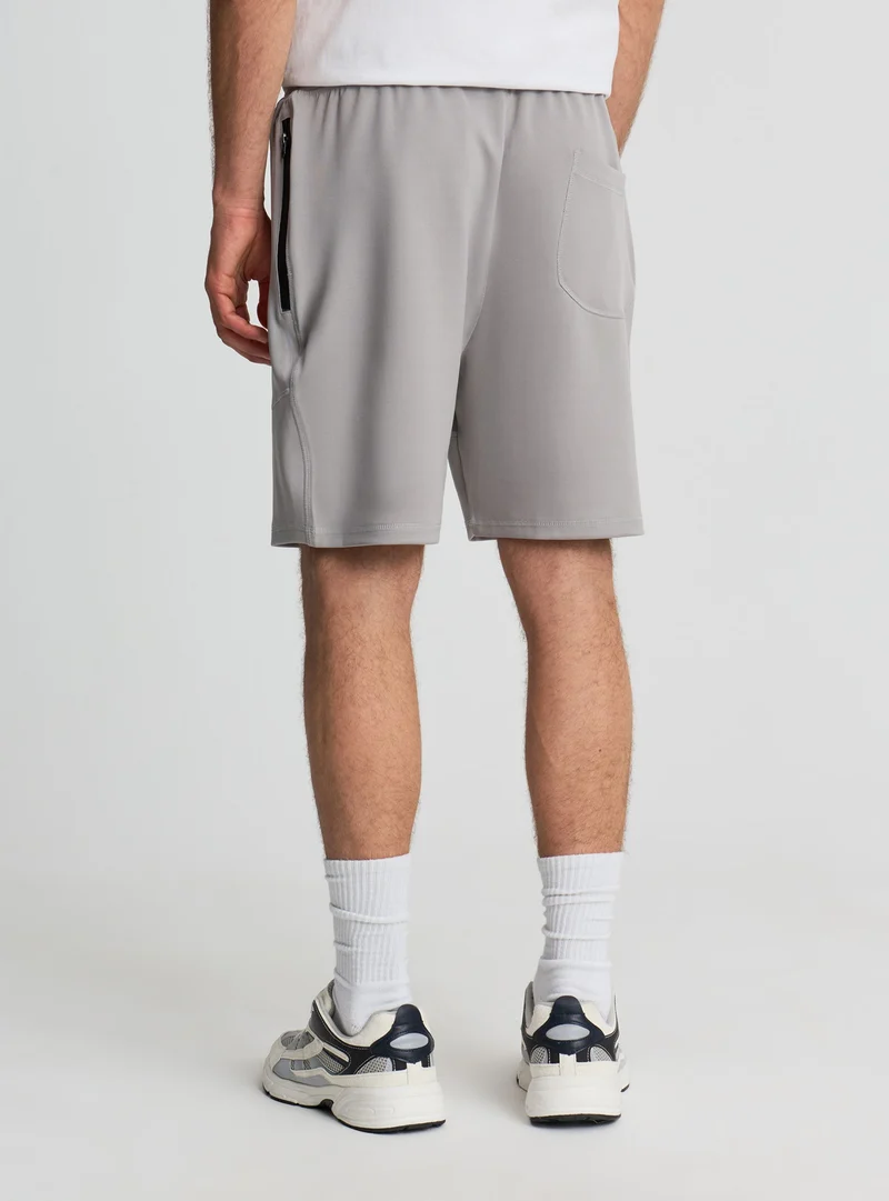 Pantaloni tuta tecnici a tinta unita con zip e tagli