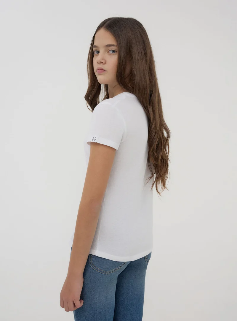 T-shirt tinta unita con etichetta sulla manica