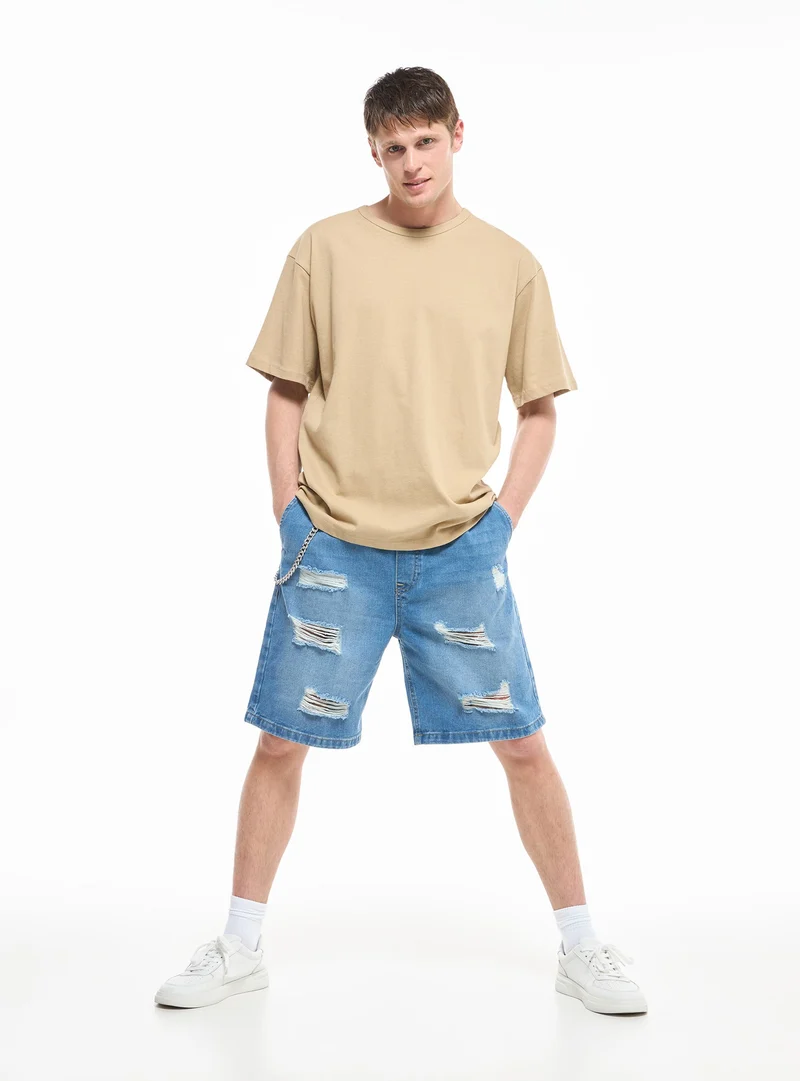 Pantaloncini jeans loose con strappi e catena